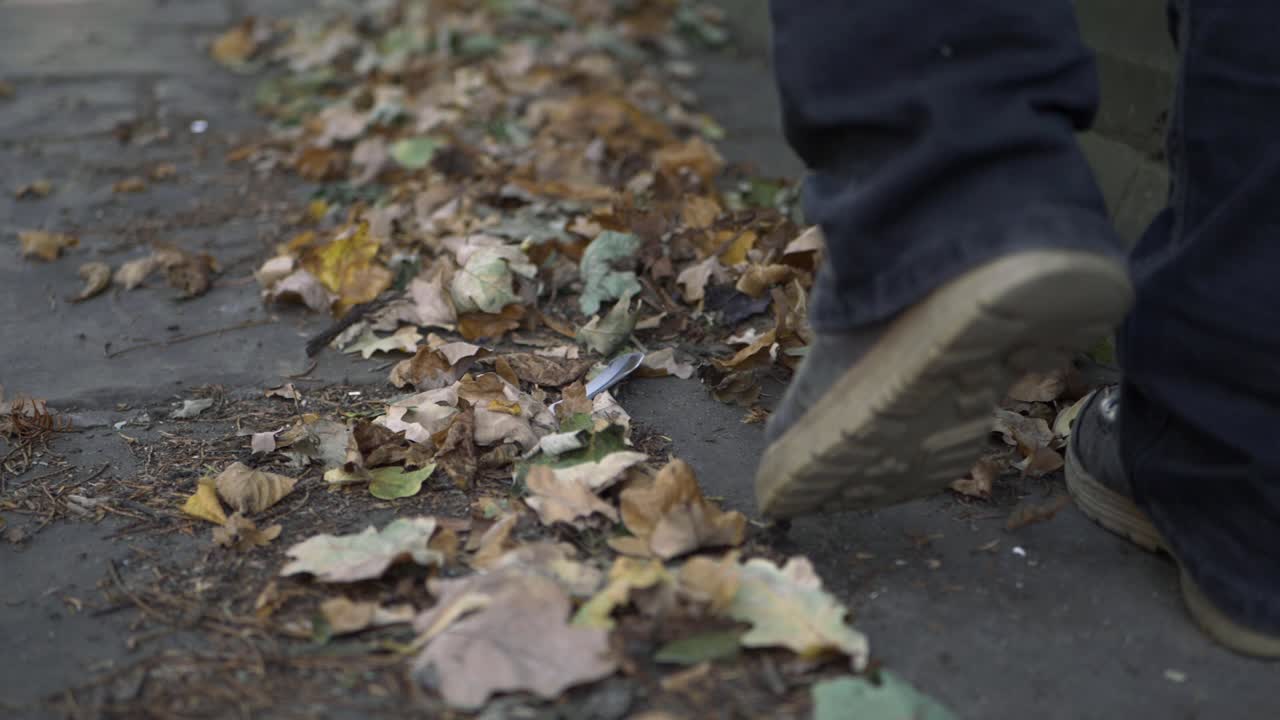 Legs kicking autumn leaves on a pathway close up shot