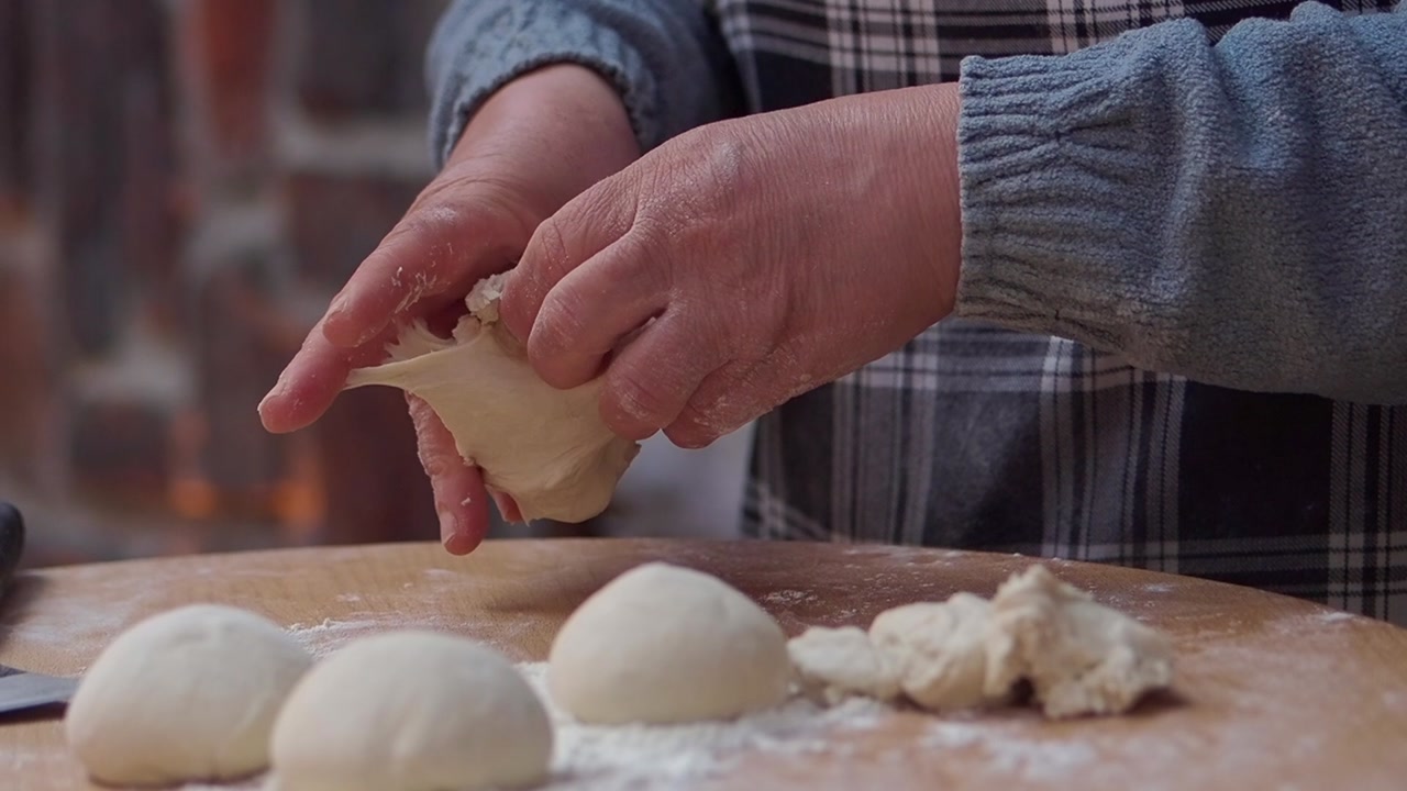 Close-up of Hands Preparing Dough for Baking on a Wooden Board