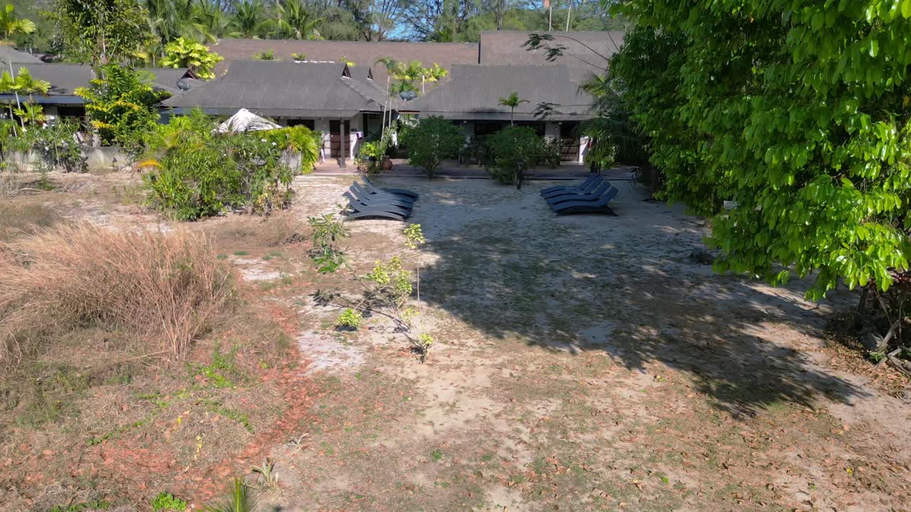 활기찬 푸른 숲 속에 자리 잡은 외 해변 리조트의 훌륭한 공중 풍경 비행, 평화로운 휴양지를 보여줍니다.