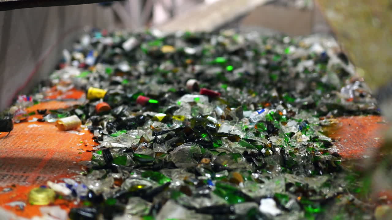 Process of sorting glass garbage on a vibrating conveyor belt at waste sorting plant. Slow motion