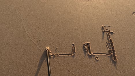 “alif baa” written by hand on beach sand,enjoying outdoor summer activities