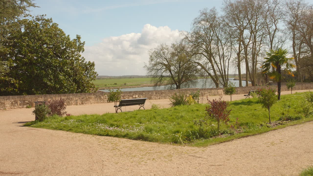 Experience the beauty of the Corderie Gardens on a sunny summer day in France, featuring vibrant greenery, peaceful benches, and stunning natural scenery.