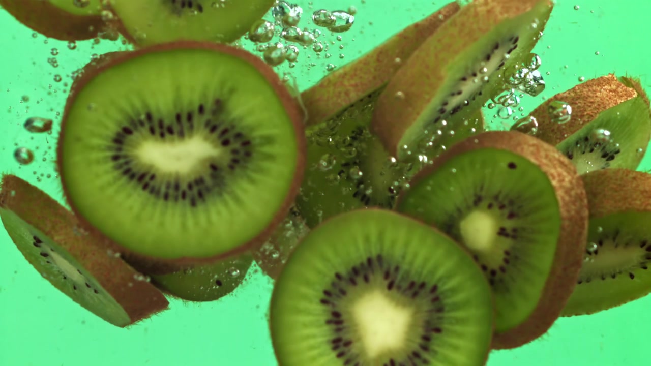 Rodajas de kiwi verde fresco cayendo y salpicando en el agua