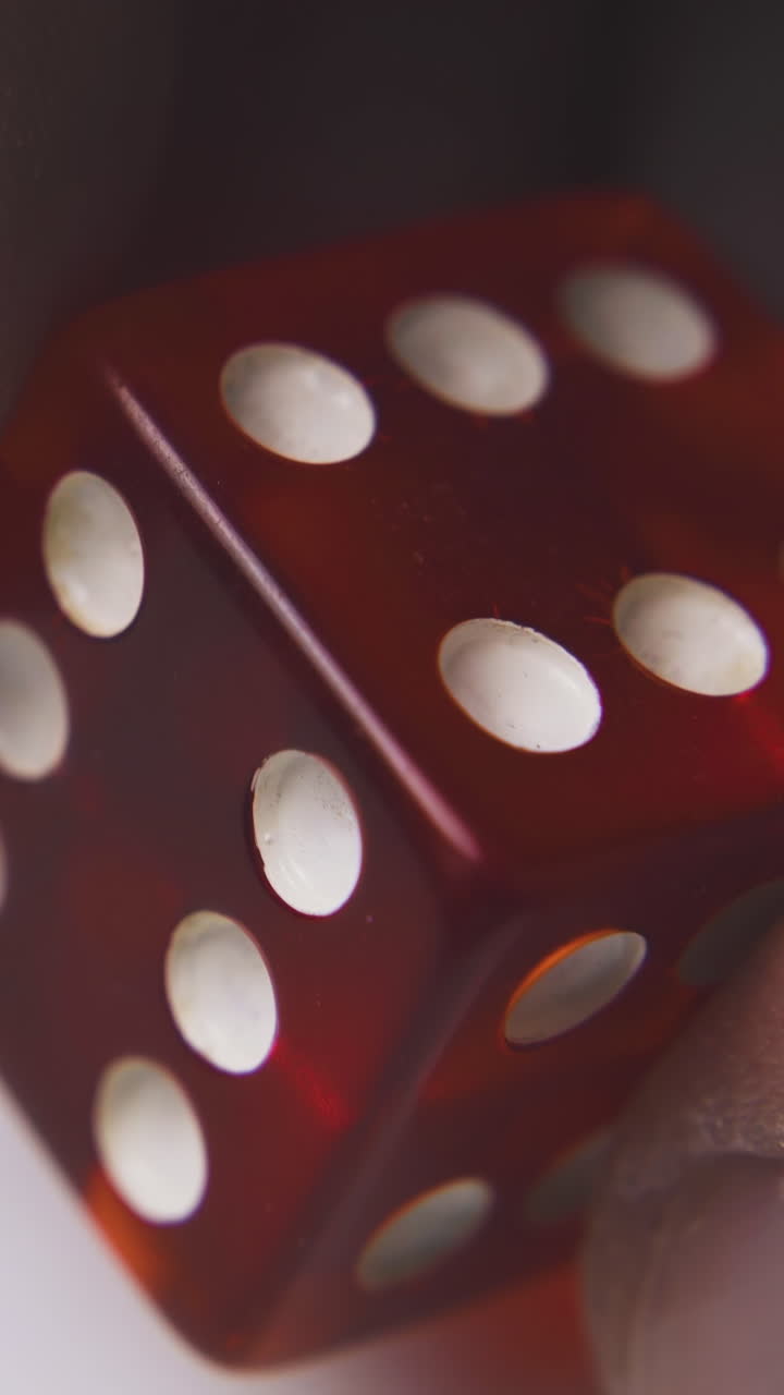 man holds red plastic transparent dice with symbol six of spots on sides on white background extreme close view