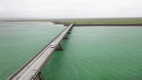 puente sobre el agua en islandia con conducción de automóviles con video de drones detrás
