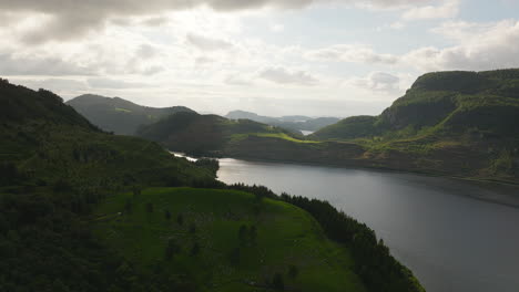 Lake-in-lush-and-dramatic-Norwegian-landscape-at-sunset,-aerial-view