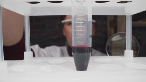 el médico gira el tubo de ensayo de plástico con la escala y la muestra de sangre