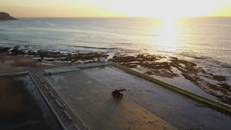 antena giratoria del amanecer: el tractor limpia la piscina vacía de mereweather en la playa