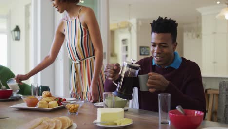 tres generaciones de familia afroamericana desayunando sentados juntos en la mesa de comedor en casa