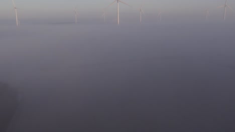 Revelar-Toma-De-Aerogeneradores-De-Grupo-Por-Encima-De-La-Niebla-Baja-Durante-El-Amanecer,-Antena