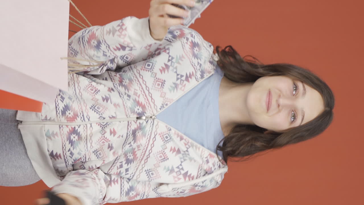 전화로 쇼핑하는 젊은 여성의 수직 비디오.