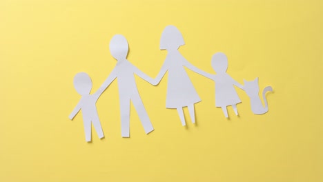 close up of family with cat made of white paper on yellow background with copy space