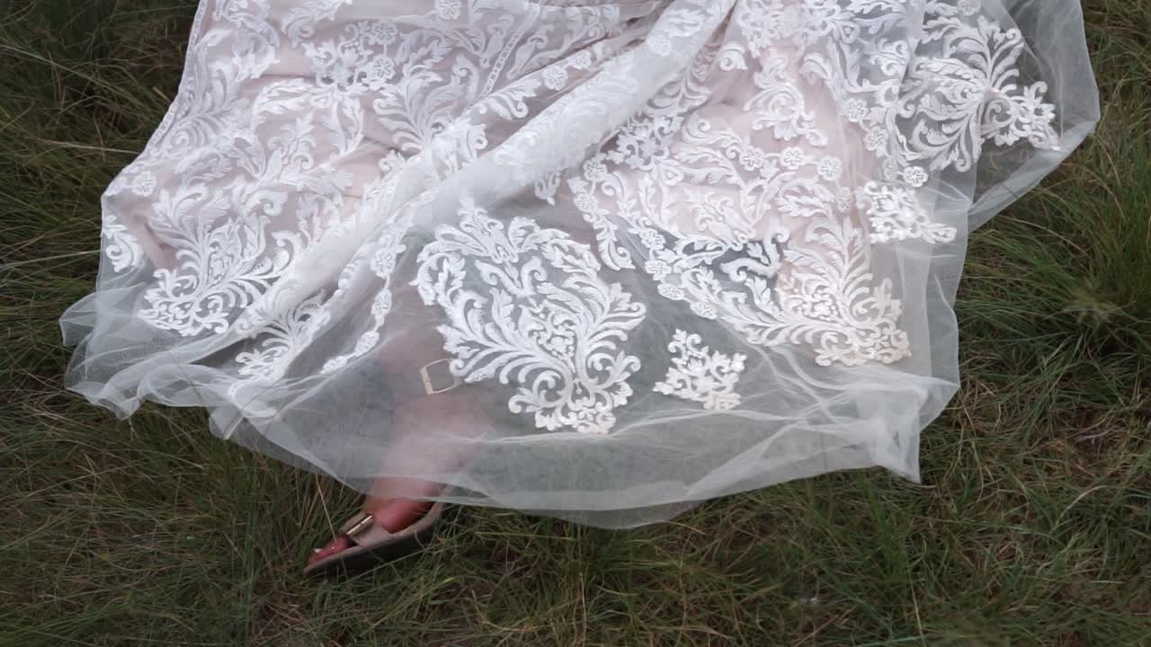 신부가 잔디 위에 누워 있는 동안 웨딩 드레스 하반부의 움직이는 샷