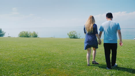 Young-Multi-Ethnic-Couple-Walking-Along-Green-Meadows-Go-Forward-Where-Beautiful-Clouds-Are-On-The-H