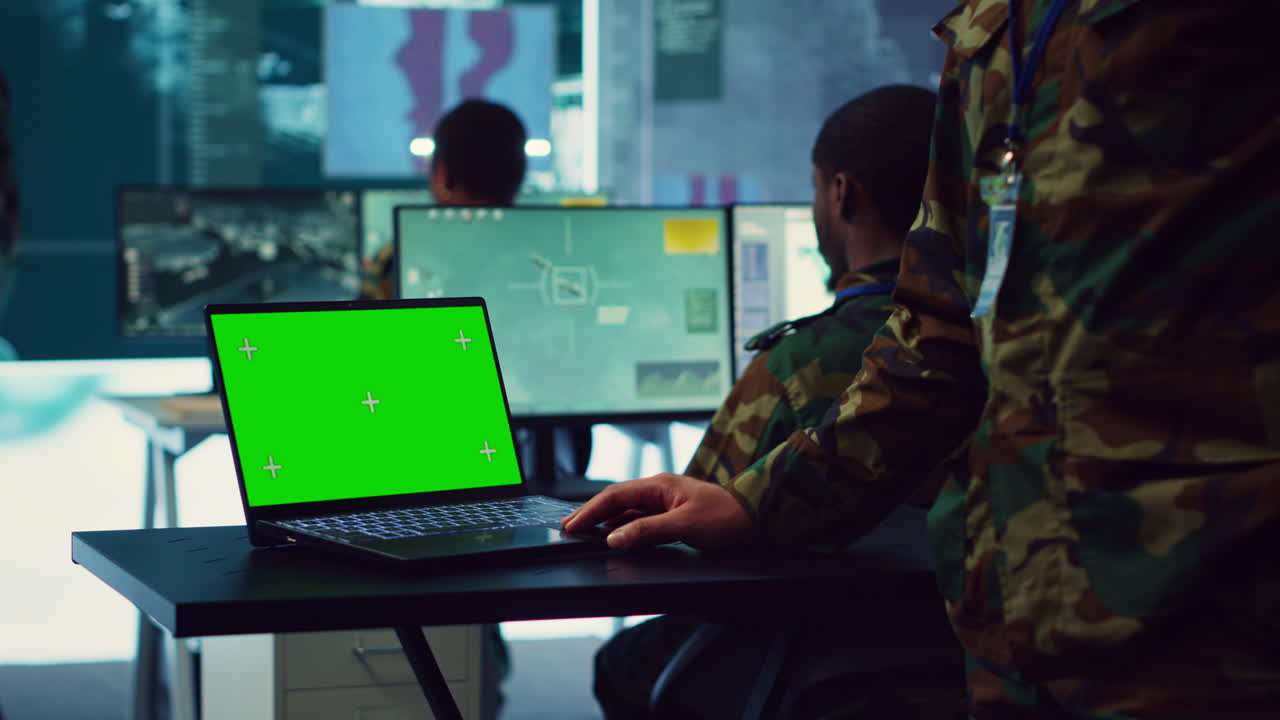 oficial del ejército estudia una pantalla verde aislada en una computadora portátil en la sala de control