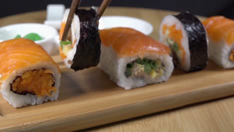 removing a peice of sushi from a serving board with chopsticks