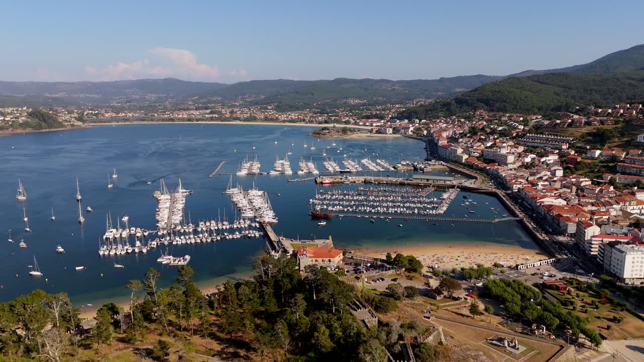 Aerial view of Baiona Marina with boats docked, surrounded by clear waters and hilly terrain
