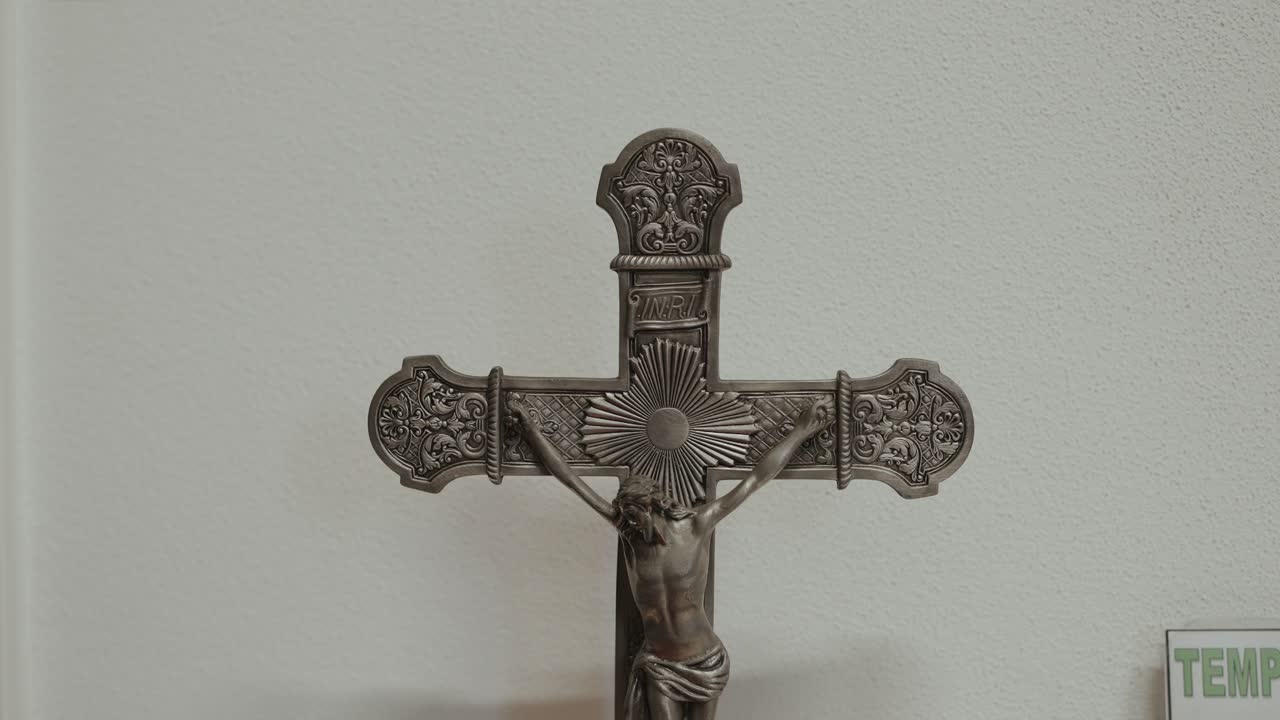 Close view of metal crucifix with Jesus figure on white church wall