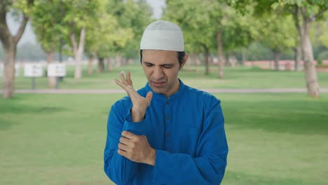 sick muslim man suffering from hand pain in park