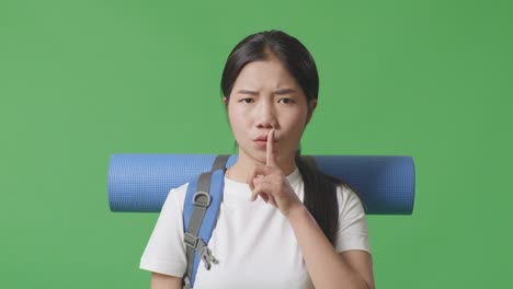 woman with backpack and finger on lips