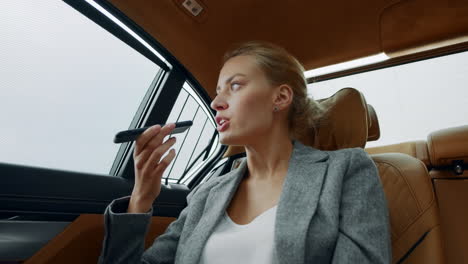 close up serious business woman recording voice message on mobile phone at car.