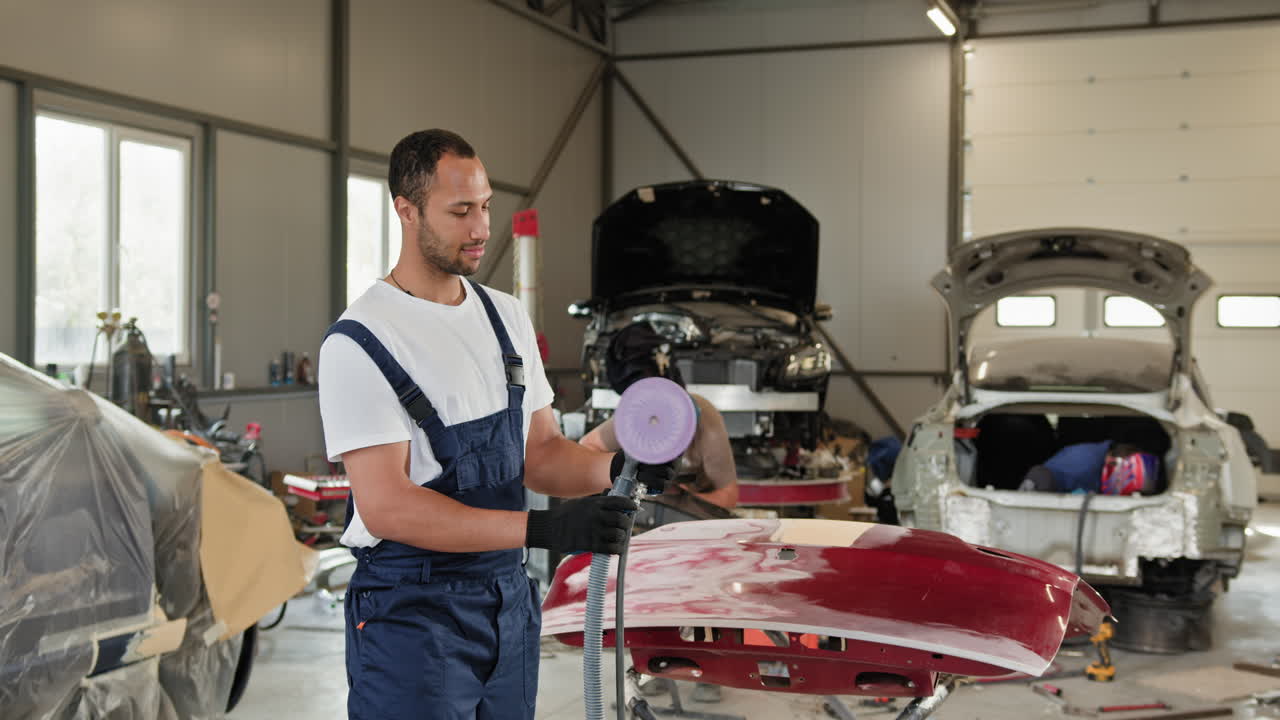 un reparador de automóviles pule el parachoques de un automóvil en un garaje