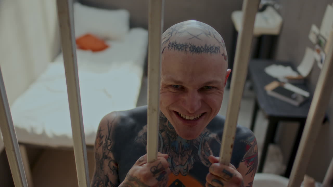 Tattooed Inmate Threatening and Laughing on Camera in Prison Cell