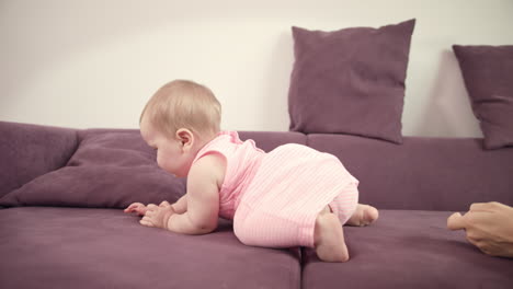 baby crawling away mother. cheerful kid walking on sofa