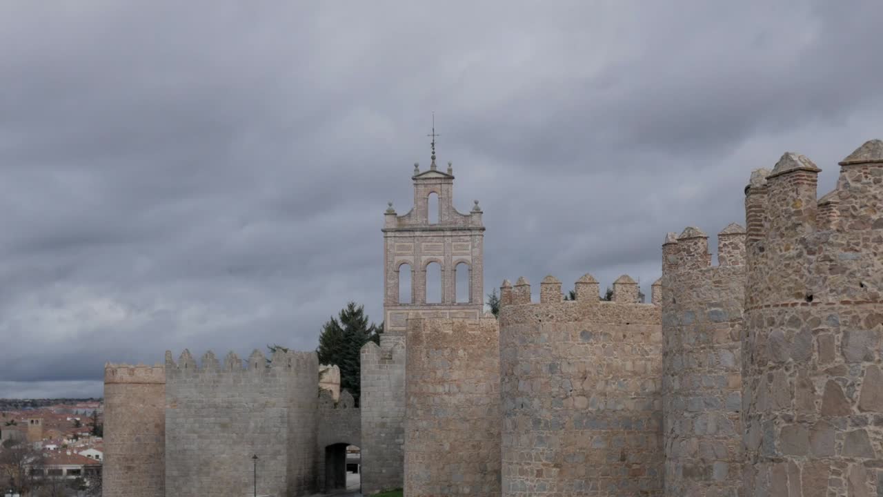 Avila city walls and a bell tower under a cloudy sky, showcasing historical architecture