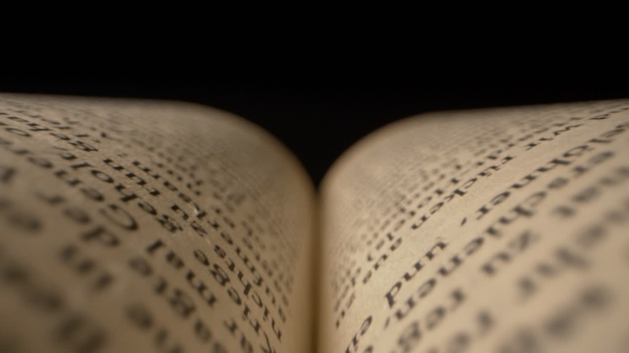 moody macro shot tirando a través de las páginas de un libro con una luz de atenuación arriba