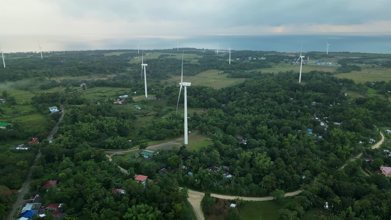 Aerial overview of San Lorenzo Wind Farm, Guimaras, with scattered wind turbines amid tropical island villages and greenery - Philippines