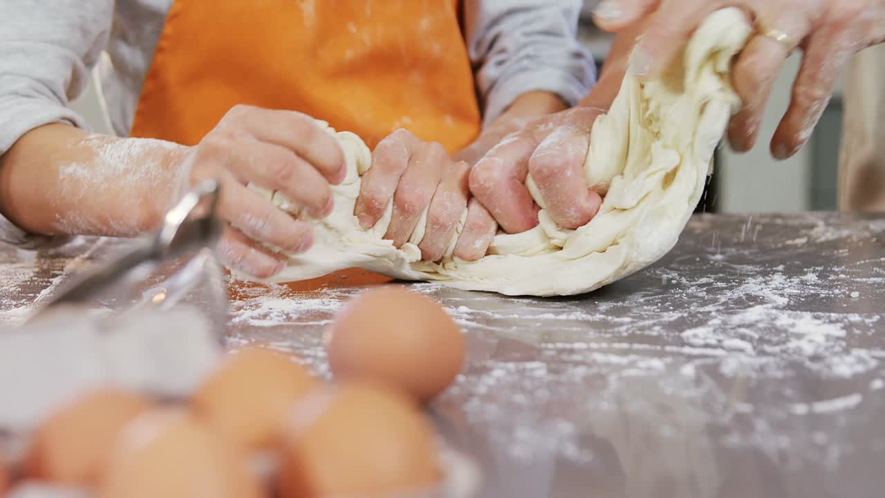 Happy grandmother and child kneading dough on kitchen table 4K 4k
