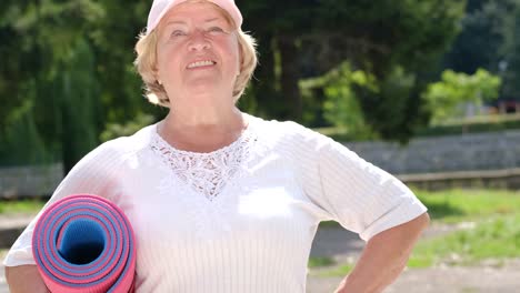 happy and smiling retired woman she goes to fitness training with a mat in her hands happy and smiling retired woman she goes to fitness training with a mat in her hands retired sports life
