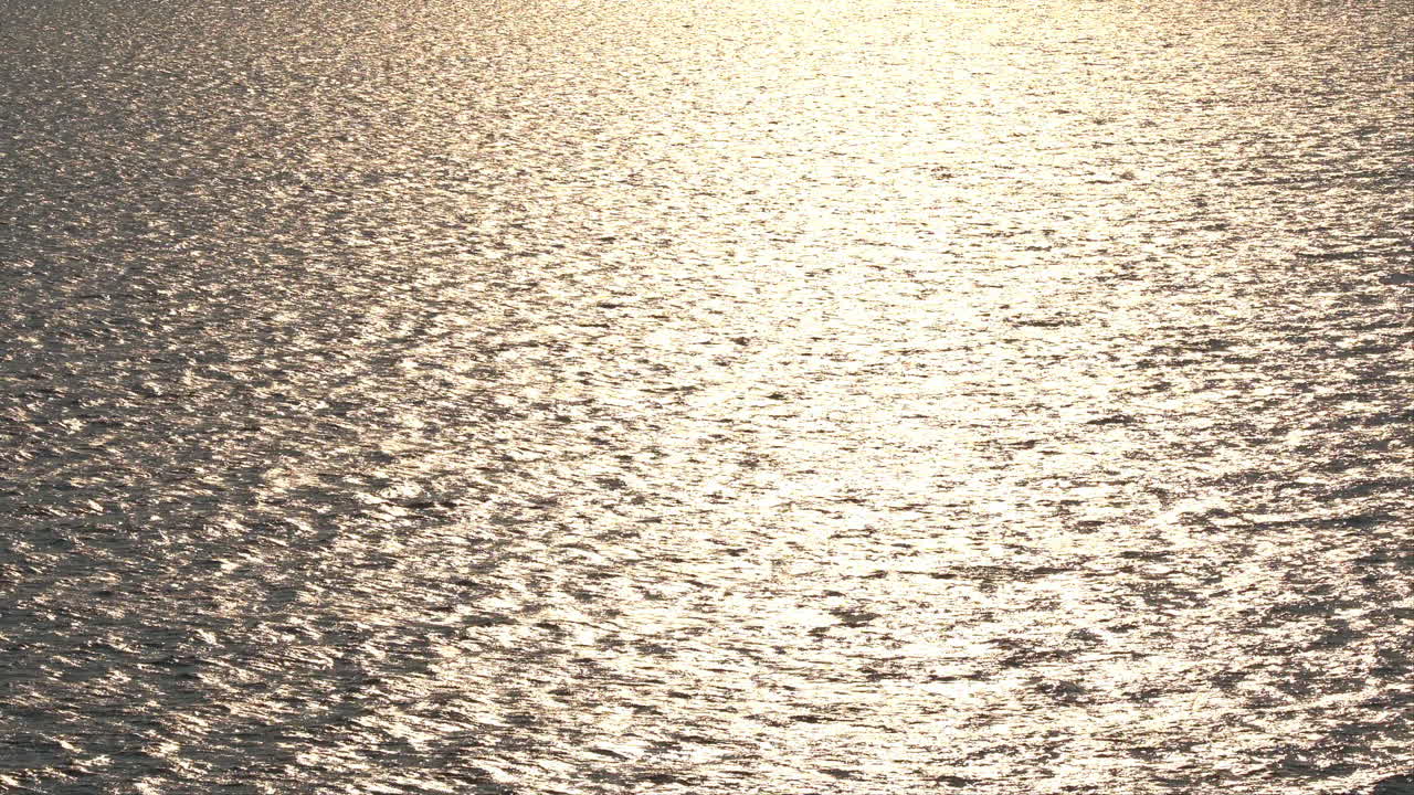 cámara lenta de agua de mar con una ligera ondulación brillando a la luz del atardecer