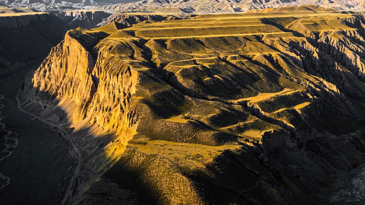 En glidende drone starter flyvning, afslører et solbeskinnet plateau og en klippe med terrasser i den gyldne time.