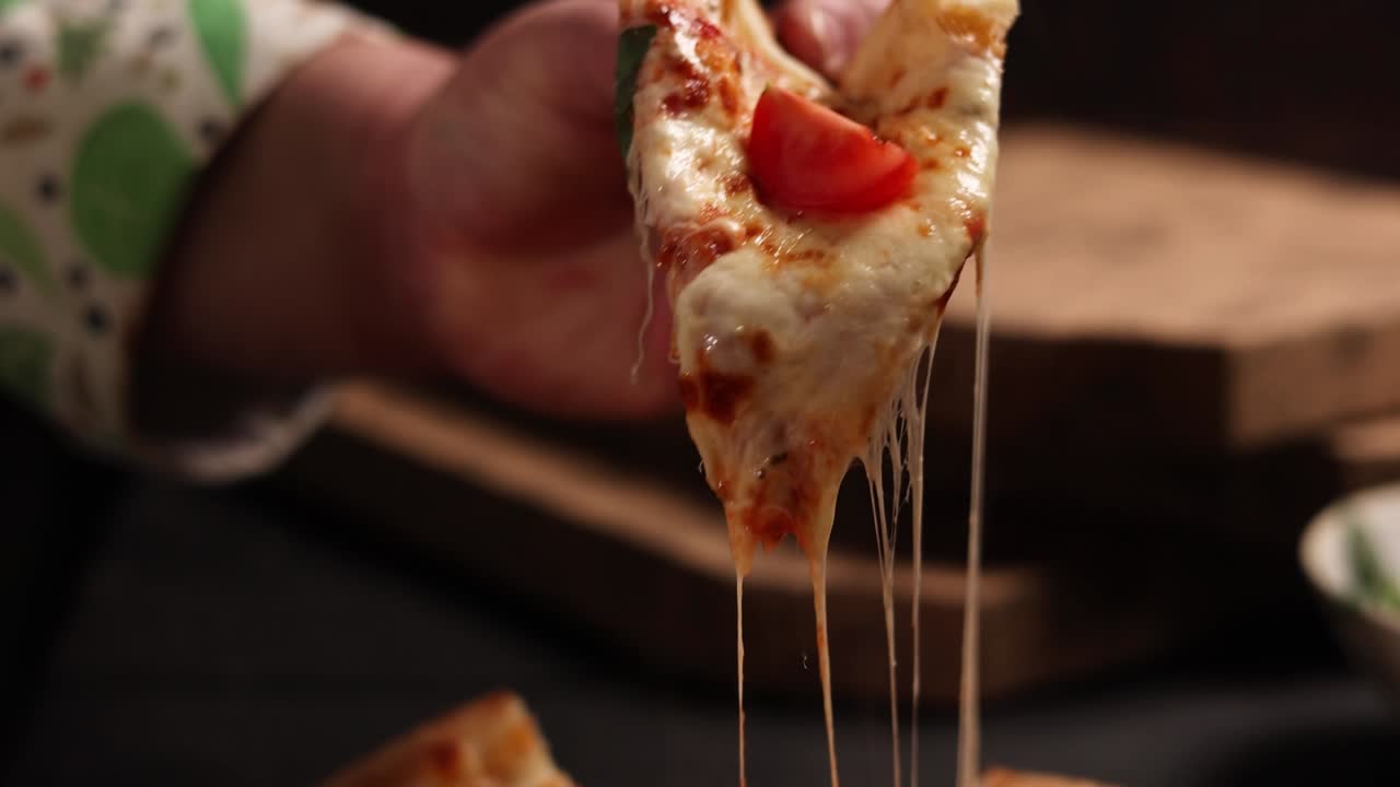 맛있는 피자 조각을 들고 있는 손의 근접