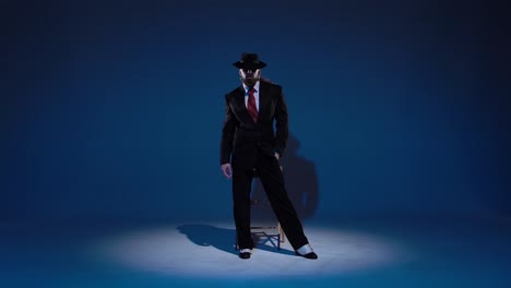 man in black suit and fedora posing in spotlight