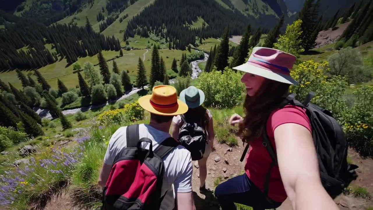 Toma en primera persona de amigos haciendo senderismo por un sendero de montaña en un día soleado