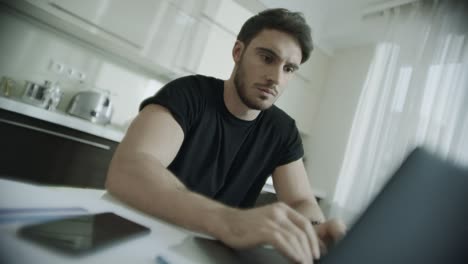 Serious-man-typing-laptop-at-home.-Business-man-using-computer-at-kitchen