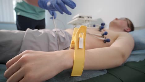 cardiac examination in a hospital with a professional cardiograph. the patient lies on a bed with connected sensors.