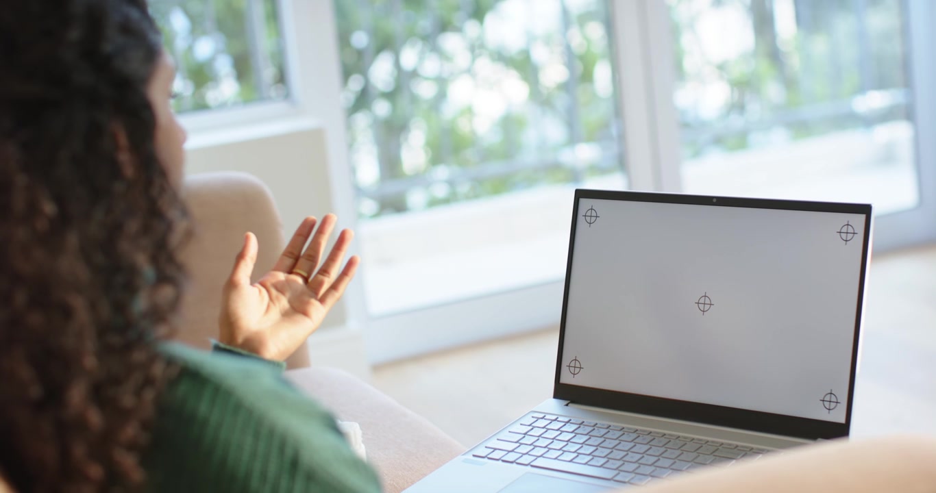 Woman is presenting from cupped palms into raised wave toward laptop on couch, camera moving closer