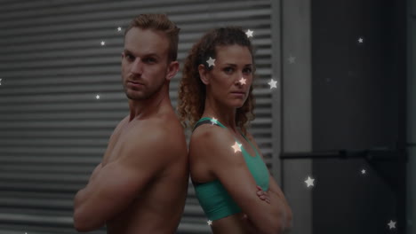 Back-to-back-fitness-models-posing-with-stars-animation-over-industrial-background