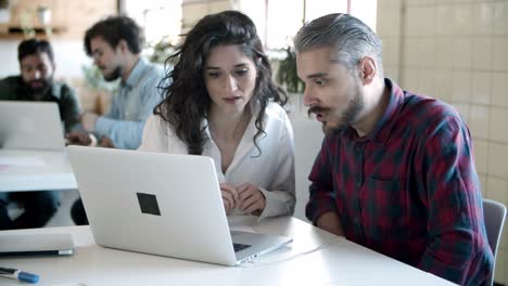 smiling young woman talking with confident bearded colleague