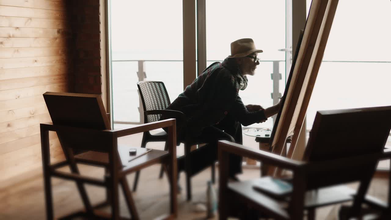 Artista che dipinge in uno studio con vista sull'oceano