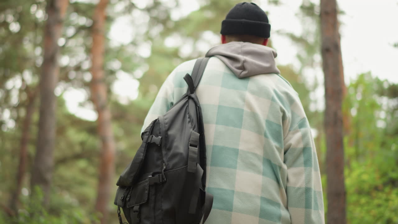 Escursionista che sistema le cinghie, persona che sistema l'attrezzatura su un sentiero nel bosco, escursionista che fissa le cinghie dello zaino durante una vivace passeggiata nel bosco, avventuriero che allaccia le cinghie sullo zaino lungo un sentiero boschivo costeggiato da pini