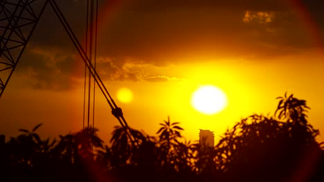 puesta de sol urbana épica que va detrás de un rascacielos con grúa de construcción y árboles ventosos después de la tormenta