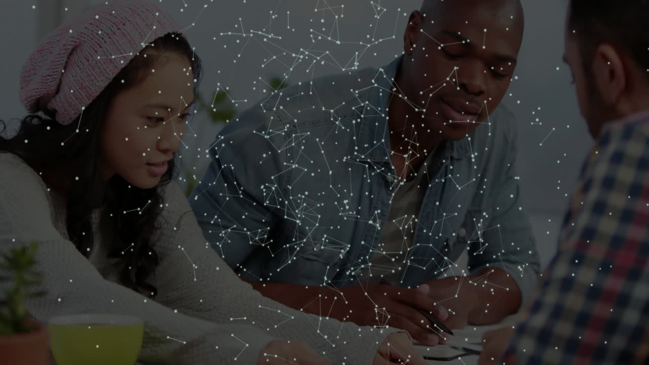 Colleagues collaborating with pen and papers in tech hub, showing network nodes overlay over desk