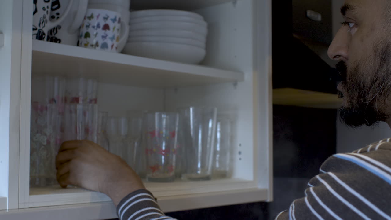 hombre en ropa casual en casa abriendo el armario blanco y sacando gafas