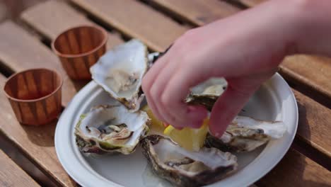 squeezing lemon over fresh oysters on a plate