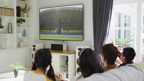 composite of happy family sitting at home together watching athletics javelin event on tv